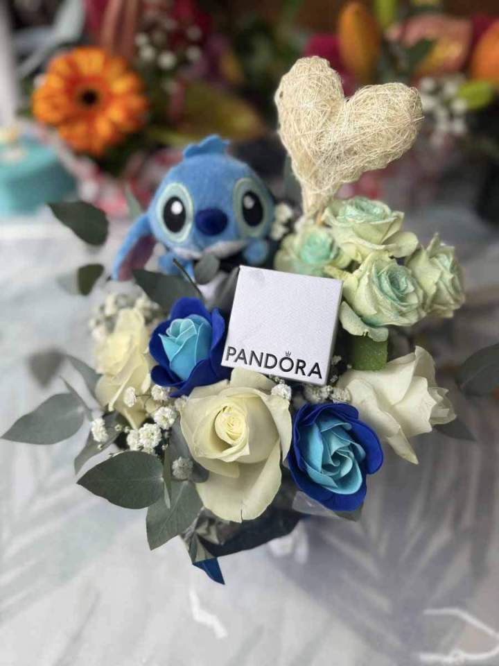 Arrangement floral avec un jouet Stitch et une carte Pandora Saint-Pierre